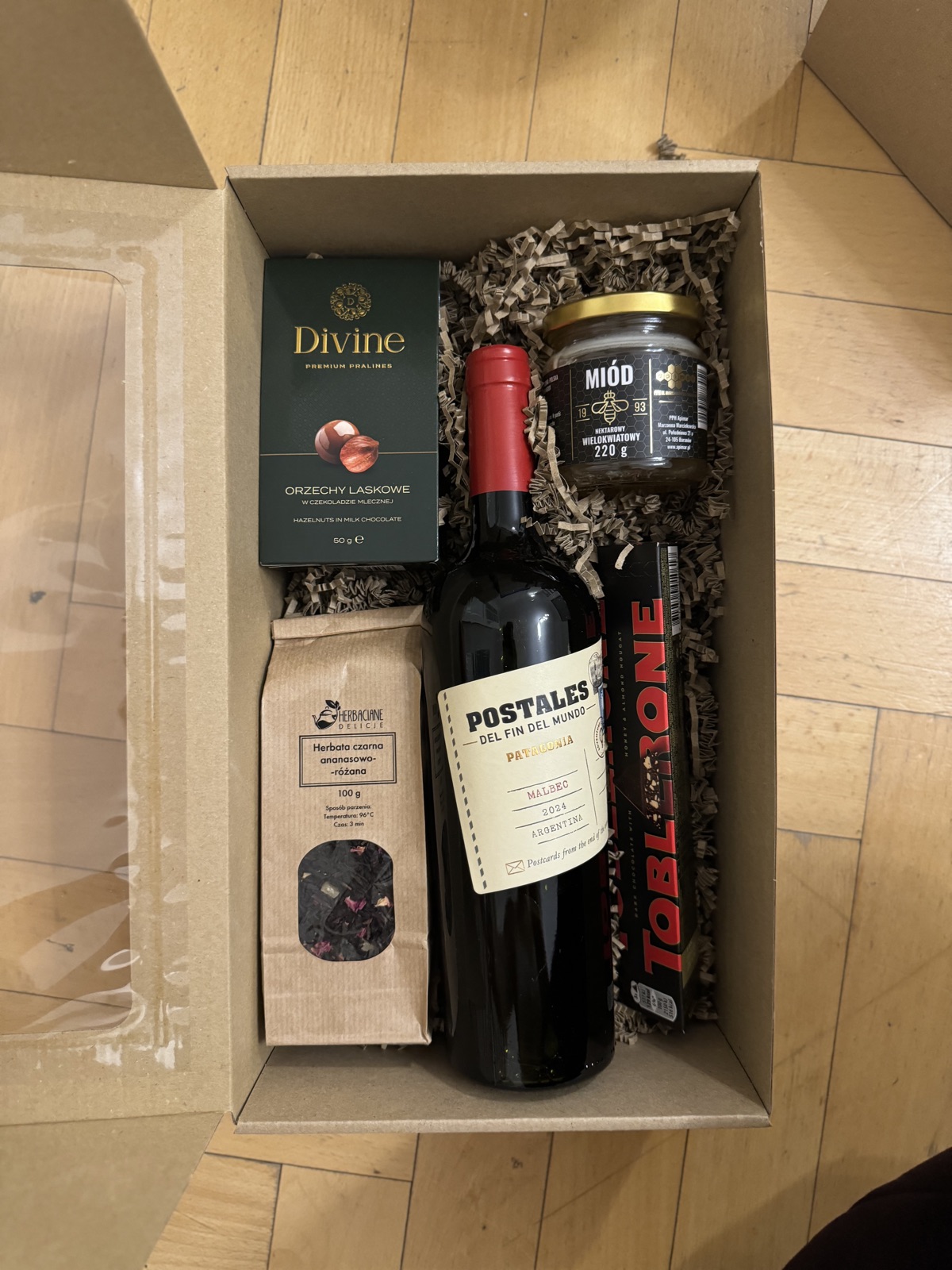 Otwarte pudełko z winem, miodem, herbatą i pralinami